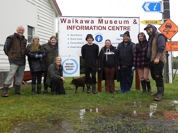 New sign out front paired with the Waikawa Museum sign - pictured from left to right: Martin, Sara, Kelsi, Jesse, Joni dog, Graydon, Misty, Mark, Keeti-Moana and Shannon.